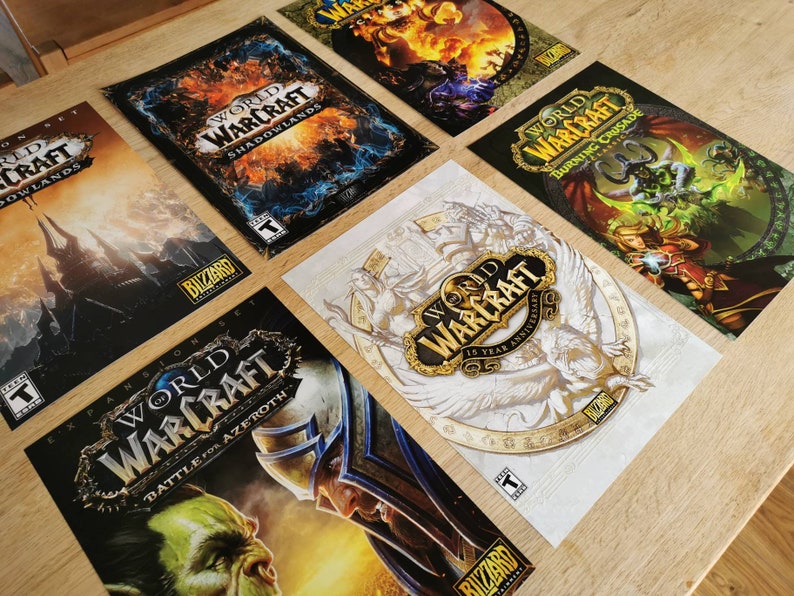 May include: A collection of World of Warcraft expansion pack covers. The covers feature different artwork and text, including "Shadowlands", "Battle for Azeroth", "Burning Crusade", and "15 Year Anniversary".