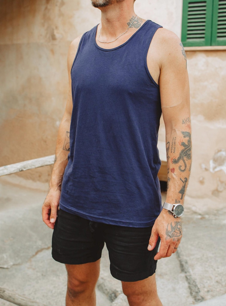 Puede incluir: Una camiseta sin mangas de color azul marino s&oacute;lido con cuello redondo y tirantes anchos, combinada con pantalones cortos negros. La camiseta presenta un dise&ntilde;o sencillo sin estampados con un dobladillo recto que cae a la cadera, de tela lisa.