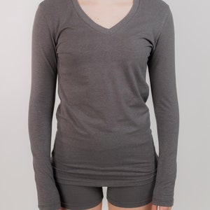 May include: A long-sleeved, charcoal gray V-neck shirt with a relaxed fit.