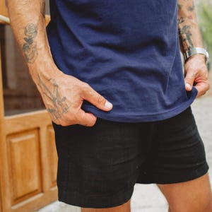 Puede incluir: Una camiseta azul marino de manga corta combinada con pantalones cortos negros. La camiseta presenta un cuello redondo sencillo y un dobladillo recto. Los pantalones cortos negros est&aacute;n cortados por encima de la rodilla y tienen un dise&ntilde;o limpio.