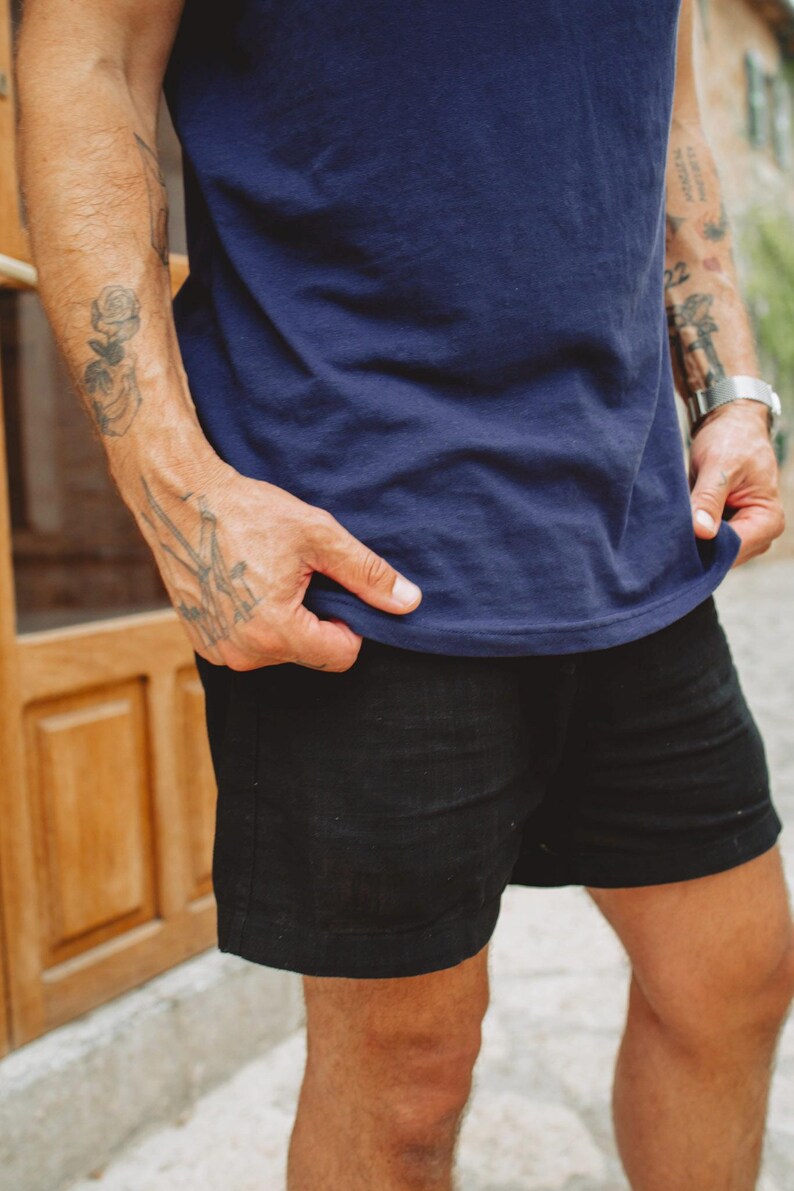 Puede incluir: Una camiseta azul marino de manga corta combinada con pantalones cortos negros. La camiseta presenta un cuello redondo sencillo y un dobladillo recto. Los pantalones cortos negros est&aacute;n cortados por encima de la rodilla y tienen un dise&ntilde;o limpio.