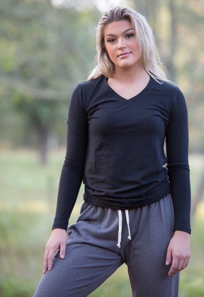 May include: A woman wearing a black long-sleeved v-neck shirt and gray sweatpants with a white drawstring.
