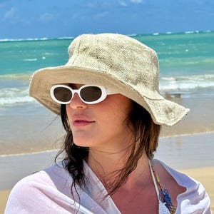 Woman on the beach wearing hemp natural solid sun hat and sun glasses.