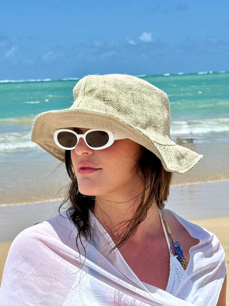Woman on the beach wearing hemp natural solid sun hat and sun glasses.