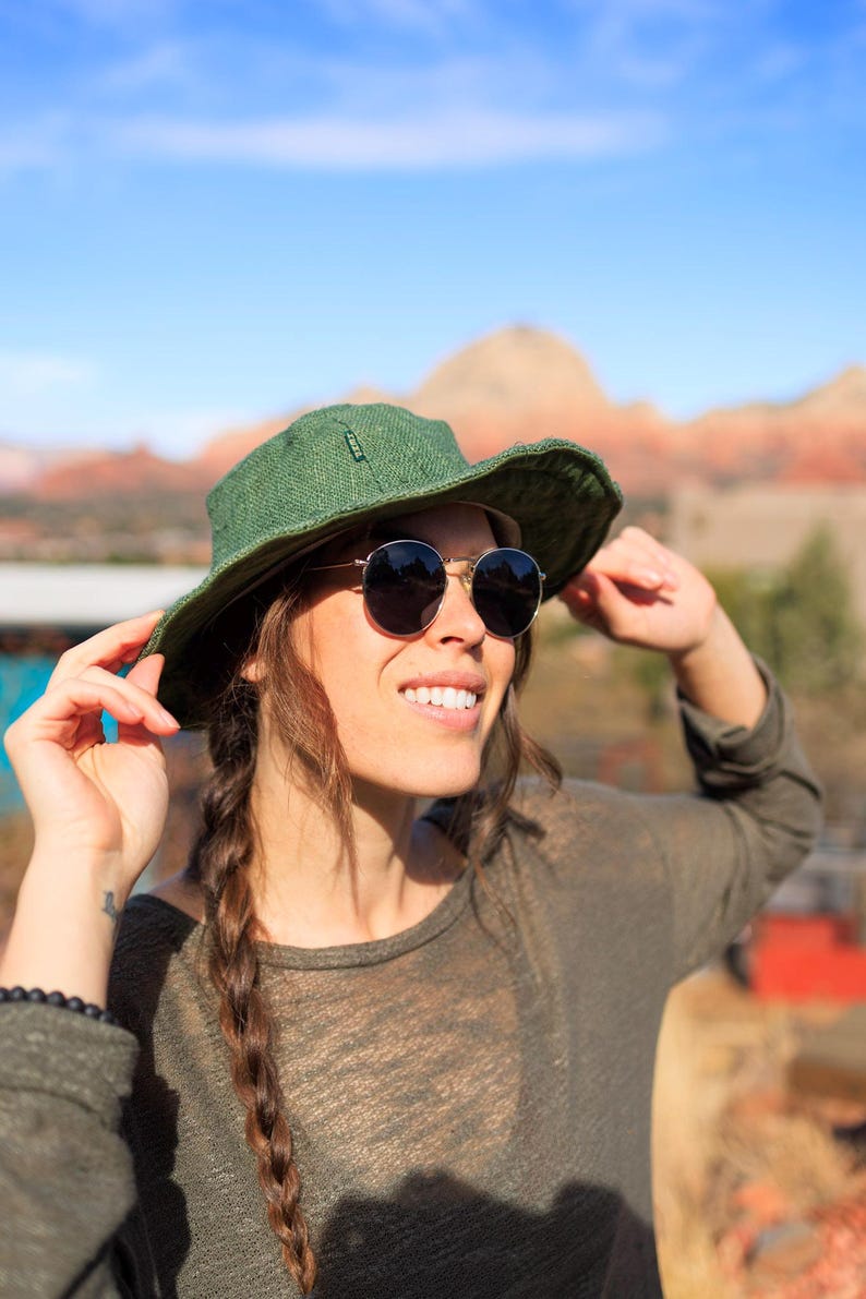 Woman wearing an olive hemp sun hat with sun glasses on.