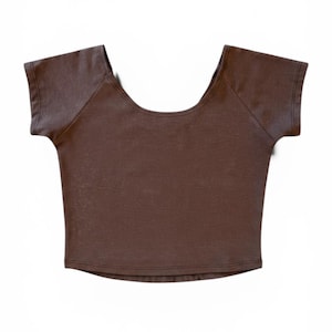 Op de afbeelding: Een bruine crop top met korte mouwen en een ronde hals. De top heeft een getailleerde vorm en een minimalistisch design. De stof lijkt een zacht gebreid materiaal te zijn. Het is een veelzijdig kledingstuk.