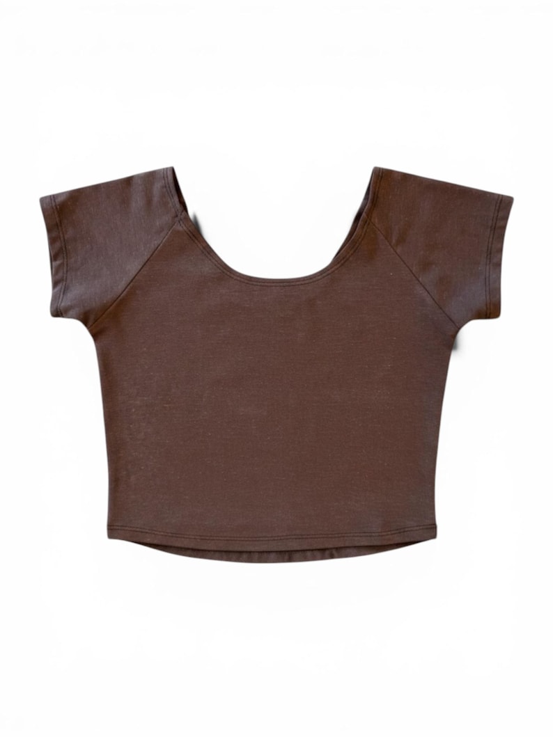 Op de afbeelding: Een bruine crop top met korte mouwen en een ronde hals. De top heeft een getailleerde vorm en een minimalistisch design. De stof lijkt een zacht gebreid materiaal te zijn. Het is een veelzijdig kledingstuk.