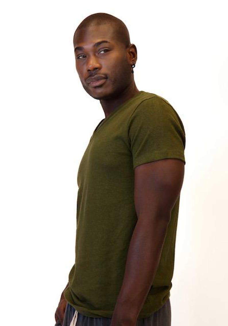 May include: A short-sleeved V-neck t-shirt in a solid olive green color. The garment features a simple, clean design with a standard fit, short sleeves, and a V-shaped neckline, crafted from a soft, textured fabric in a deep, earthy tone.