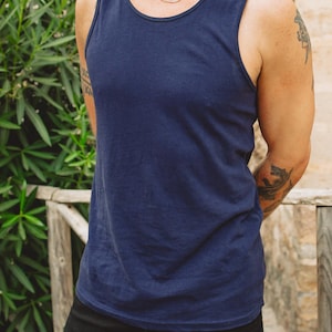 Puede incluir: Una camiseta de tirantes azul marino lisa sin mangas con cuello redondo. La prenda presenta un dise&ntilde;o sencillo y limpio con tirantes anchos y un dobladillo recto, ofreciendo una pieza de ropa b&aacute;sica y funcional para uso casual.