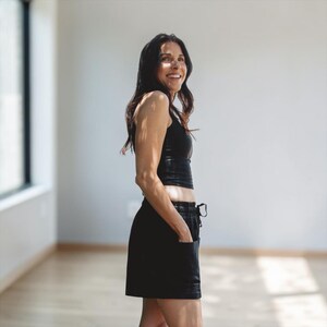 May include: A black sleeveless crop top paired with matching black shorts featuring an elastic waistband with a drawstring and two front pockets. The set is made of a solid black fabric and is shown from a side profile view, highlighting the fit.
