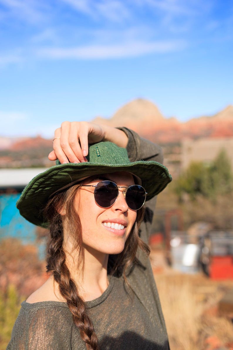 Woman wearing an olive hemp sun hat with sun glasses on.