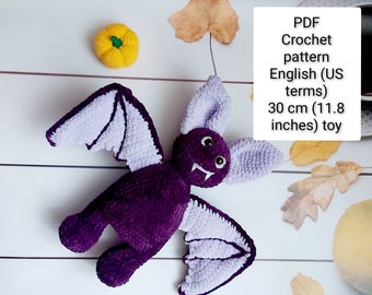 Könnte beinhalten: Lilafarbener Häkel-Fledermaus-Spielzeug mit Lavendelflügeln. Die Fledermaus ist 30 cm (11,8 Zoll) groß. Häkelanleitung als PDF in Englisch (US-Begriffe) enthalten.