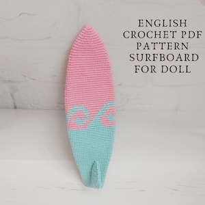 May include: A pink and blue crocheted surfboard for a doll. The surfboard has a wave design on the bottom.