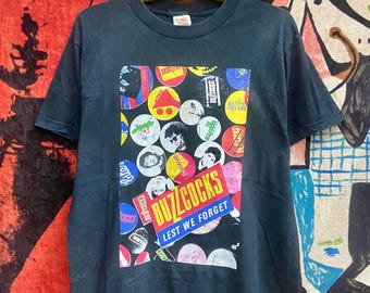 Camiseta vintage de Buzzcocks de los 90 con el álbum "Lest We Forget" de 1988, de estilo punk inglés. Cultura/New Wave/Camiseta vintage punk, talla M.