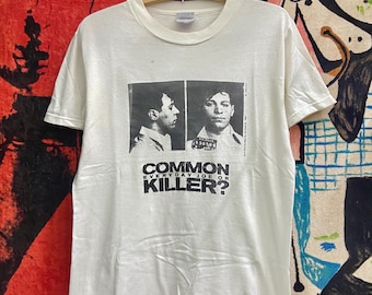 May include: White t-shirt featuring a black and white image of a man's mugshot. The text "COMMON EVERYDAY JOE OR KILLER?" is printed below the image.