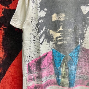 K&ouml;nnte beinhalten: Wei&szlig;es T-Shirt mit einem Schwarzwei&szlig;portr&auml;t eines Mannes mit einem blauen und rosa Design. Das Shirt hat handschriftlichen Text, darunter "Malcolm X" und "Rocket Ship".