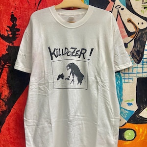 Może przedstawiać: Biała koszulka z czarno-białym nadrukiem graficznym przedstawiającym byka i mniejsze zwierzę. Tekst "KILLDOZER!" jest nadrukowany nad grafiką.