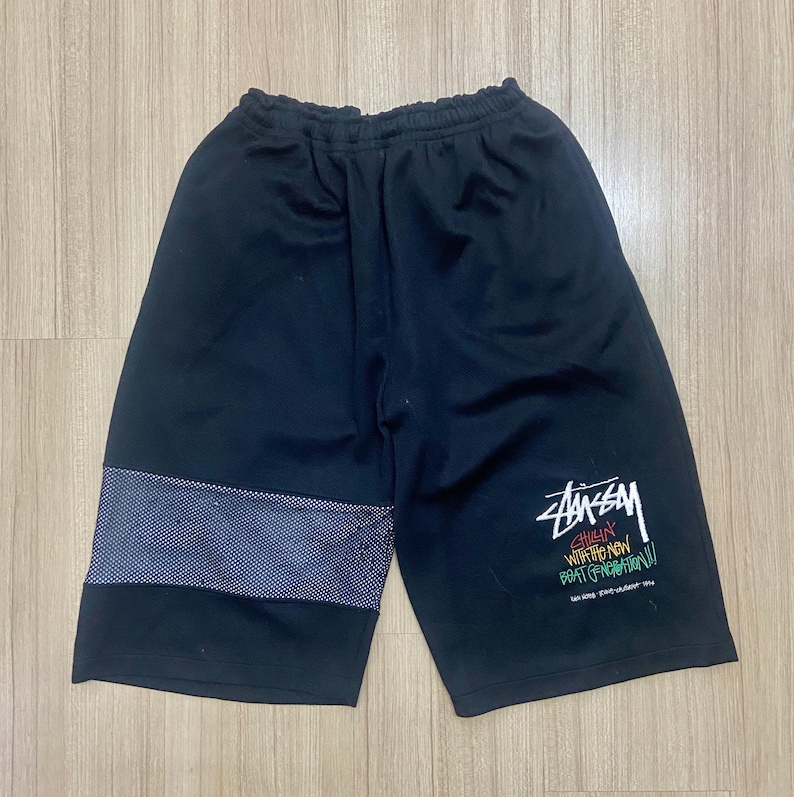 Puede incluir: Pantalones cortos deportivos negros con un panel de malla y cintura el&aacute;stica. Los pantalones cortos presentan el logotipo de Stussy y texto en blanco, verde y rojo. Los pantalones cortos est&aacute;n hechos de un material suave y c&oacute;modo.