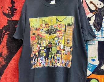 May include: Dark grey t-shirt with a vibrant print of a bustling London street, including red buses and crowds. The design includes text: "WINTER LONDON - PICCADILLY CIRCUS". A vintage-style graphic tee.