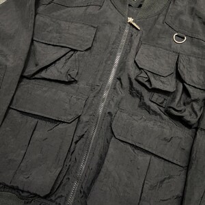 Peut inclure: Veste de bombardier noire avec plusieurs poches avant et une fermeture &eacute;clair. La veste pr&eacute;sente un col et des poignets c&ocirc;tel&eacute;s, et un petit &eacute;cusson logo. Le logo The North Face est visible.