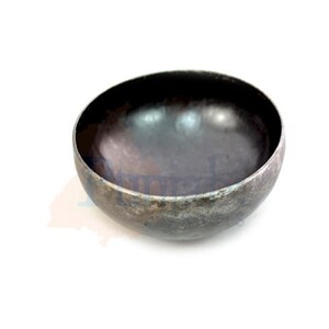 May include: A round, black metal bowl with a slightly hammered finish. The bowl is empty and has a smooth, reflective surface.