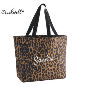 Könnte beinhalten: Eine Tragetasche mit Leopardenmuster in Braun- und Schwarztönen. Die Tasche hat schwarze Henkel und den Namen "Sandra" in weißer Schrift. Der Text "Druckwelt" ist ebenfalls sichtbar. Ein stilvolles Accessoire.