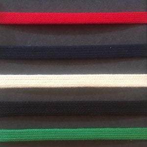 May include: A sample card with seven different coloured fabric strips labelled with the words "Tub Rouge", "Tub Navy", "Tub Naturel", "Tub Noir", "Tub Vert", "Tub Orange", and "Tub Coffee".