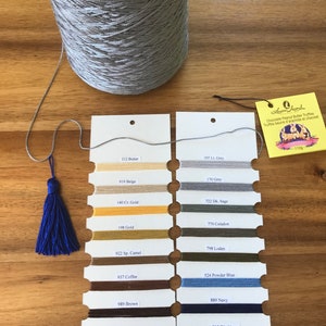 May include: A large spool of silver-grey thread with a matching tassel. Colour swatches display various thread colours, including beige, gold, brown, and navy. A tag reads "Chocolate Peanut Butter Truffles" and "110g."