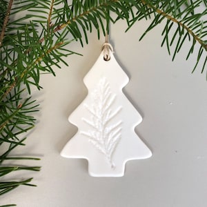May include: White ceramic Christmas tree ornament with a pine needle design.