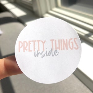 May include: A white round sticker with the text "PRETTY THINGS inside" in pink and gray lettering.