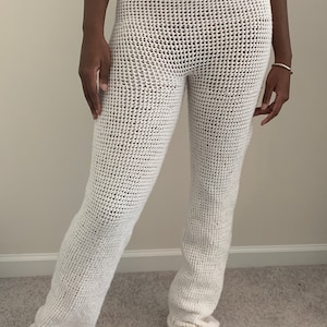 May include: White crochet pants with a wide leg and a cuffed bottom.