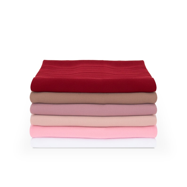 May include: Stack of five fabric squares in various shades of pink, red, and brown. The fabric is smooth and has a slight sheen.