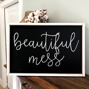 May include: A white framed black chalkboard sign with the text "beautiful mess" written in white cursive script.