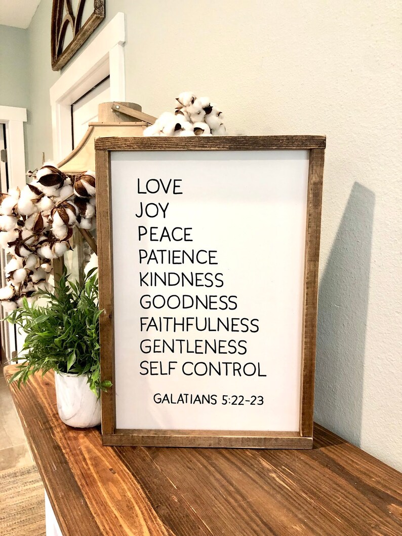 May include: A framed wood sign with white background and black text. The text reads "Love, Joy, Peace, Patience, Kindness, Goodness, Faithfulness, Gentleness, Self Control, Galatians 5:22-23".