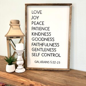 May include: A wooden sign with the text "LOVE, JOY, PEACE, PATIENCE, KINDNESS, GOODNESS, FAITHFULNESS, GENTLENESS, SELF CONTROL, GALATIANS 5:22-23" in black lettering.