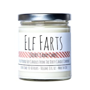 May include: A glass jar candle with a silver lid. The label reads "ELF FARTS (SCENT: CANDY CANE)" and "HAND POURED SOY CANDLES FROM THE DIRTY CANDLE COMPANY BURN TIME: 50-60 HOURS - VOLUME: 8 FL. OZ. - MADE IN USA".