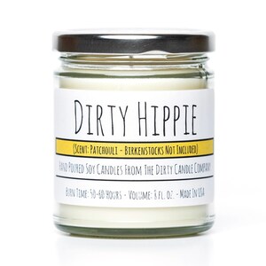 Peut inclure: Une bougie en verre dans un pot avec un couvercle argenté. L'étiquette indique "DIRTY HIPPIE" avec le parfum "PATCHOULI - BIRKENSTOCKS NOT INCLUDED". L'étiquette indique également "HAND POURED SOY CANDLES FROM THE DIRTY CANDLE COMPANY" et "BURN TIME: 50-60 HOURS - VOLUME: 8 FL. OZ. - MADE IN USA".