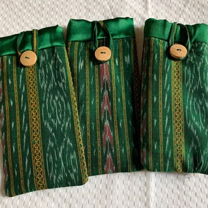 May include: Three green and gold striped fabric pouches with wooden button closures. The pouches have a green satin trim.