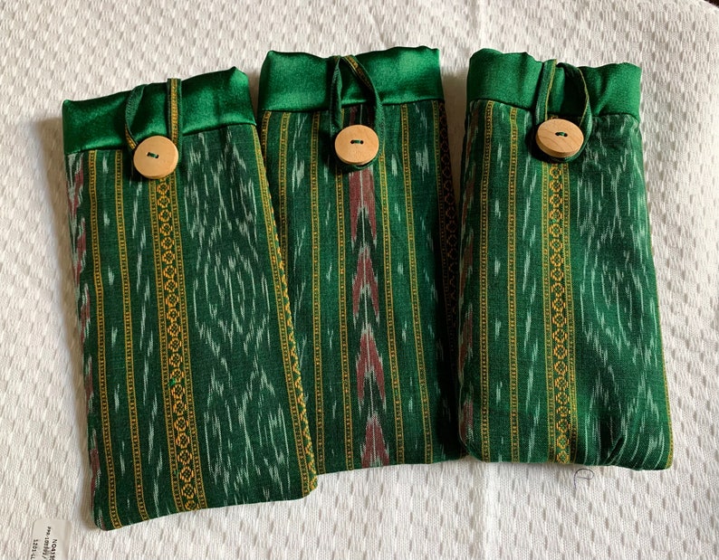 May include: Three green and gold striped fabric pouches with wooden button closures. The pouches have a green satin trim.