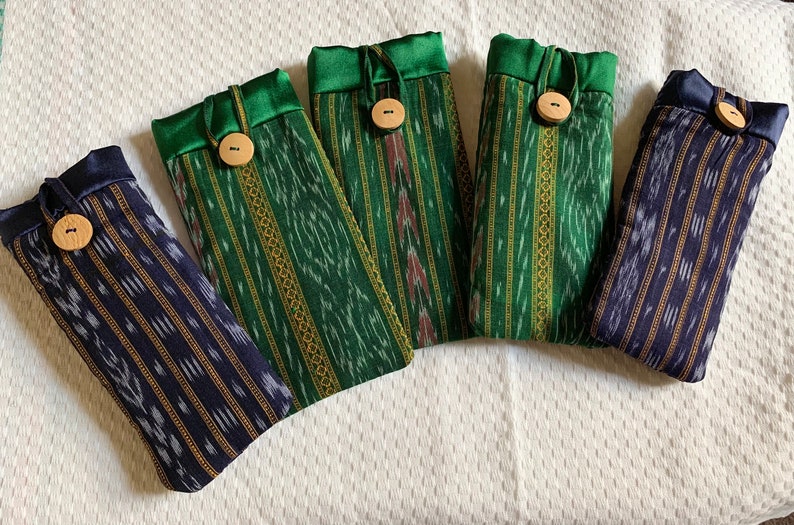 May include: Five fabric pouches with green and blue striped patterns and wooden buttons. The pouches have a drawstring closure and are lined with green satin.