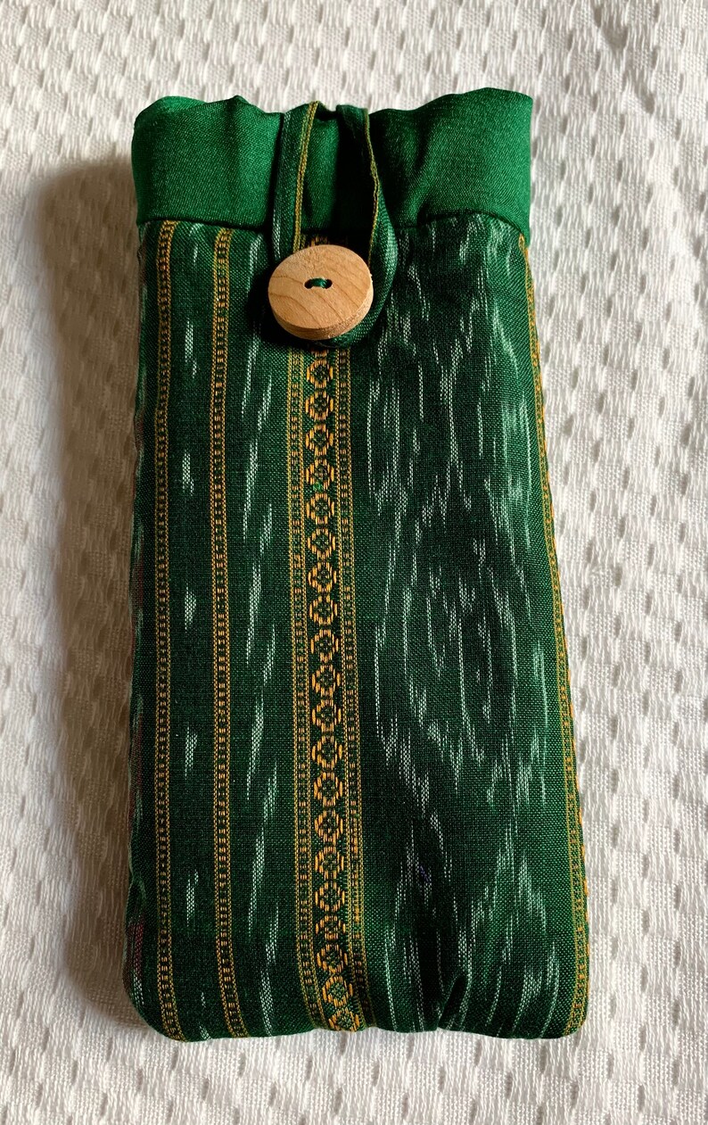 May include: A green fabric pouch with a wooden button closure. The pouch has a striped pattern with gold and white accents.