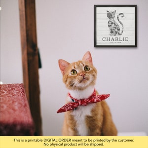 May include: Printable digital art print of a black cat silhouette made of flowers with the name Charlie and the date 10.14.2019. A ginger cat with a red bandana is looking up at the print.