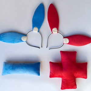 May include: Two sets of bunny ears headbands, one blue and one red, with white felt accents.  Also included are two plush pillows, one blue and one red in the shape of a cross.