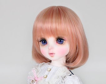 May include: A doll with pink hair wearing a blue and white dress with a lace trim. The dress has a pattern of books and hearts. The doll is wearing brown shoes.