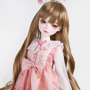 May include: A porcelain doll with long, wavy, light brown hair wearing a pink dress with a white lace collar and a white bow. The dress has a pink and white checkered pattern with a small horse design. The doll is wearing a pink bow headband.