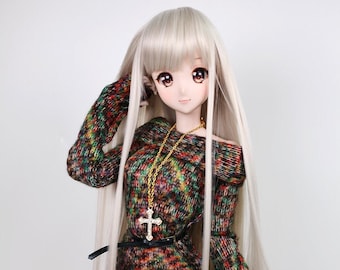 May include: A doll with long, straight, platinum blonde hair wearing a colorful, knitted sweater dress with a black belt and a gold chain necklace with a cross pendant.