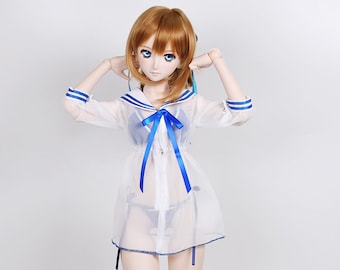 Può includere: Bambola con capelli rossicci e occhi blu, indossa un abito bianco trasparente in stile marinaio con finiture blu e un fiocco abbinato. La bambola indossa anche un bikini blu. La bambola è su sfondo bianco.