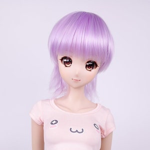 Könnte beinhalten: Eine Puppe mit lila Haaren, die ein rosa Crop-Top mit einem Comic-Gesicht und eine blaue Jeans-Shorts trägt.