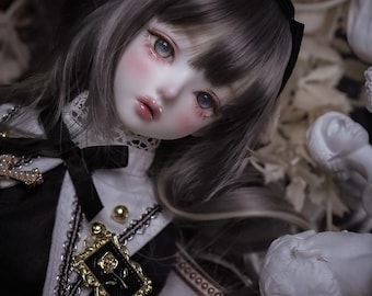 May include: A porcelain doll with long gray hair, wearing a black and white dress with a gold pendant. The doll has a delicate face with blue eyes and pink cheeks.
