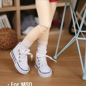 May include: White canvas high-top sneakers with black laces and a black trim around the sole. The sneakers are worn by a doll with white socks and a red skirt. The text "* For MSD" is visible in the lower left corner of the image.